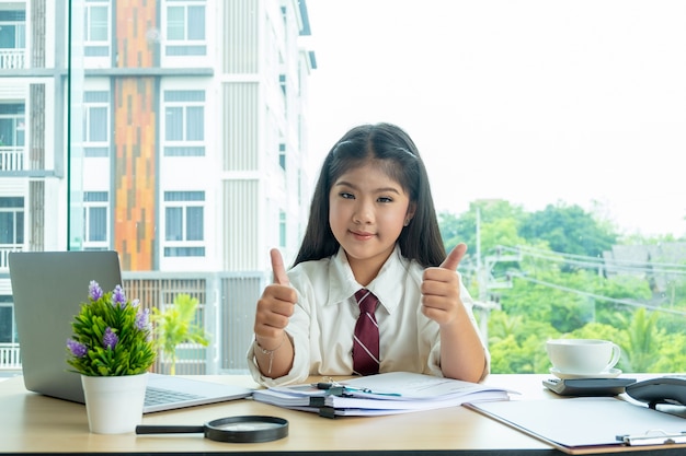 young happy girl sitting on office desk playing acting as a businesswoman