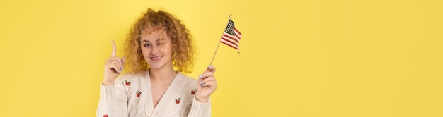 A young happy girl with a smile on her face holds an American flag in her hands Symbol of patriotism and freedom