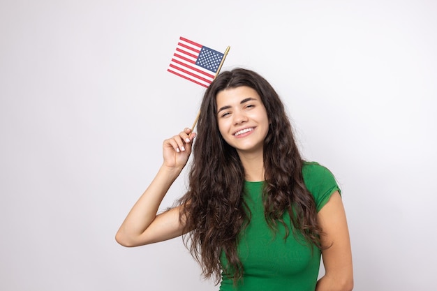 A young happy girl with a smile on her face holds an American flag in her hands Symbol of patriotism and freedom