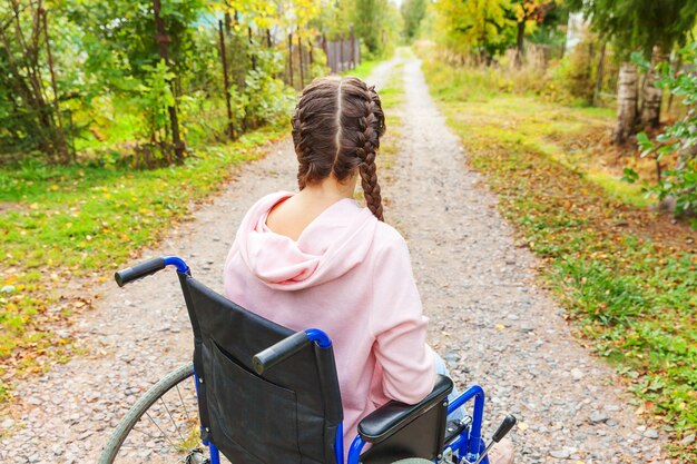 Young happy handicap woman in wheelchair on road in hospital park waiting for patient services