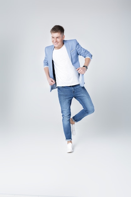 Young happy handsome man in jeans and jacket jumping