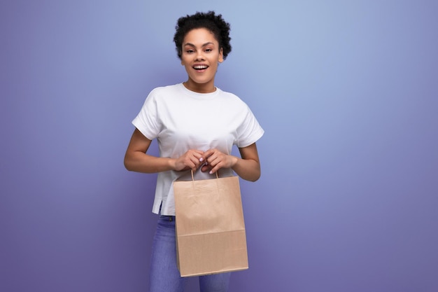 Young happy hispanic brunette woman working in a delivery service holding a craft bag in her hands