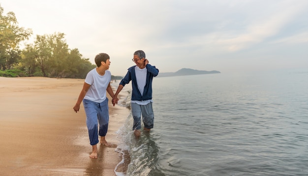 Young happy interracial couple walking on beach smiling holding around each other. 