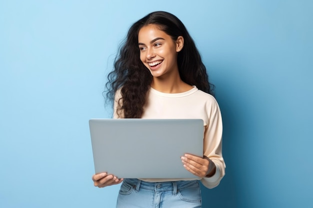 Young happy latin woman using portable device isolated on blue background