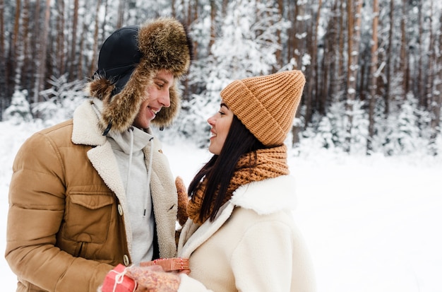 A young, happy, loving couple embrace in a snow-covered forest. Happy weekend. Valentine's Day.