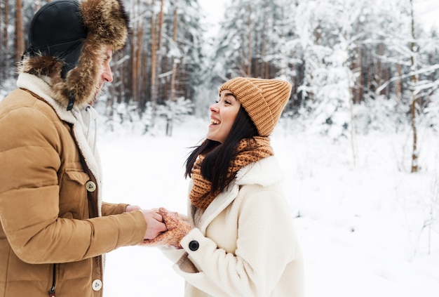 A young, happy, loving couple embrace in a snow-covered forest.