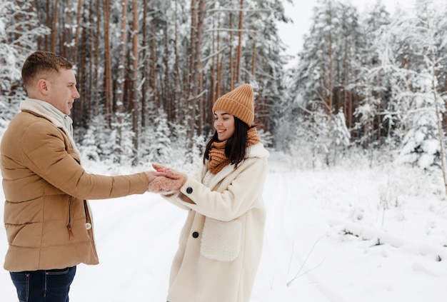 A young, happy, loving couple embrace in a snow-covered forest.