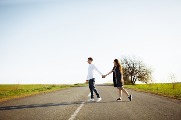 Young, happy, loving couple standing on the road holding hands and looking at each other