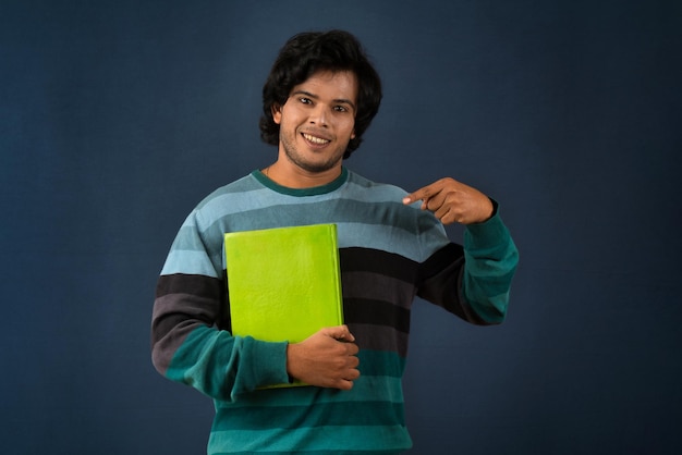 Young happy man holding and posing with the book on background