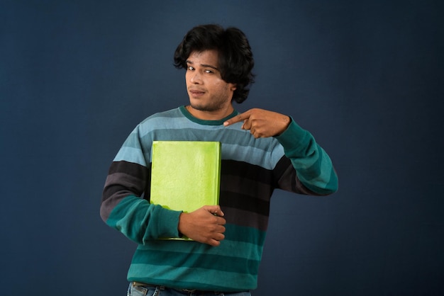 Young happy man holding and posing with the book on background