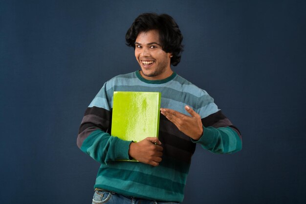 Young happy man holding and posing with the book on background