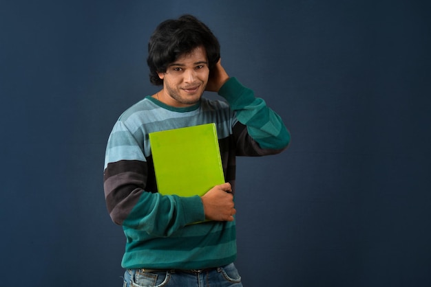 Young happy man holding and posing with the book on background