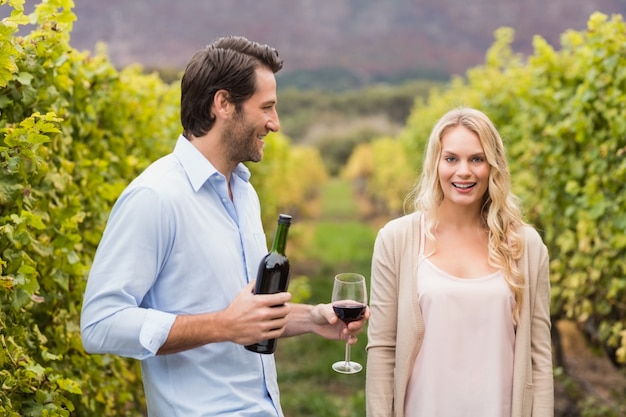 Young happy man offering wine to a young woman