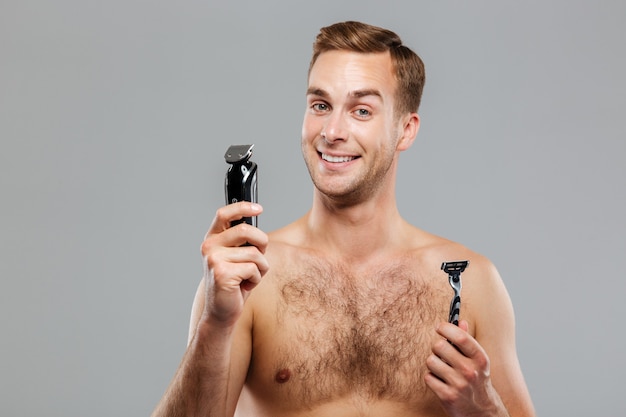 Young happy man what razor to choose isolated on the gray wall