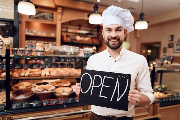 Young Happy Man with Open Sign Standing in Bakery.