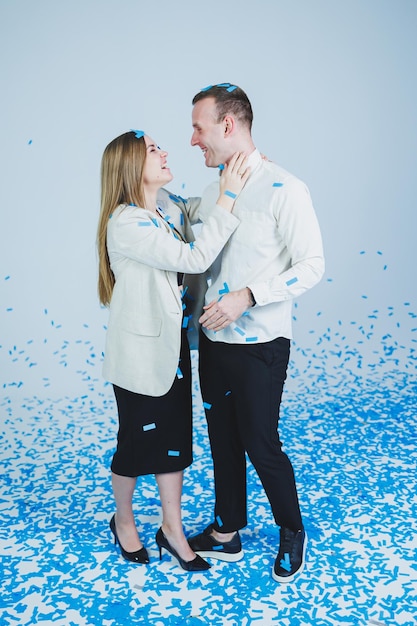 Young happy married couple hugging in blue confetti A couple in love rejoices and has fun Gender photo session