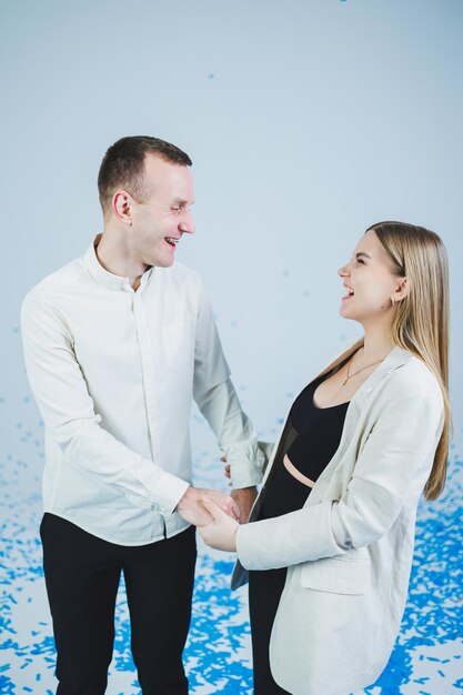 Young happy married couple hugging in blue confetti A couple in love rejoices and has fun Gender photo session