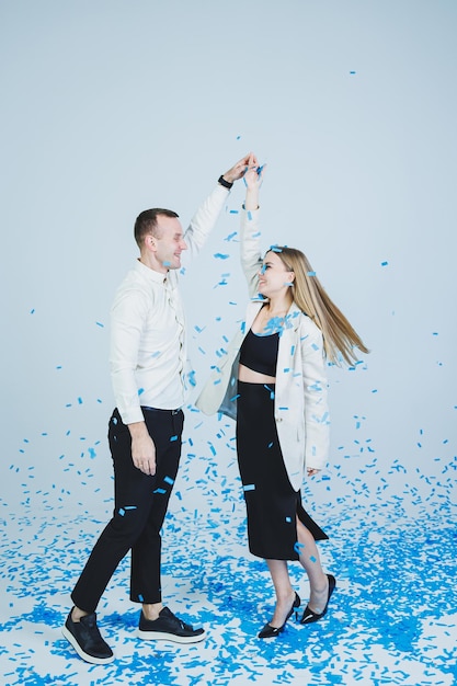 Young happy married couple hugging in blue confetti A couple in love rejoices and has fun Gender photo session