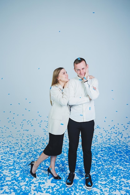 Young happy married couple hugging in blue confetti A couple in love rejoices and has fun Gender photo session