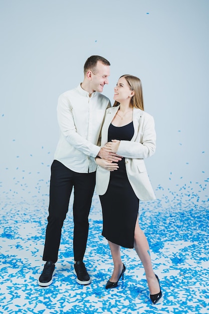 Young happy married couple hugging in blue confetti A couple in love rejoices and has fun Gender photo session