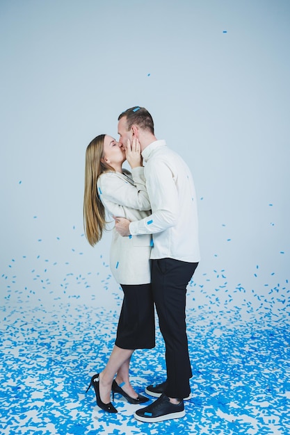 Young happy married couple hugging in blue confetti A couple in love rejoices and has fun Gender photo session