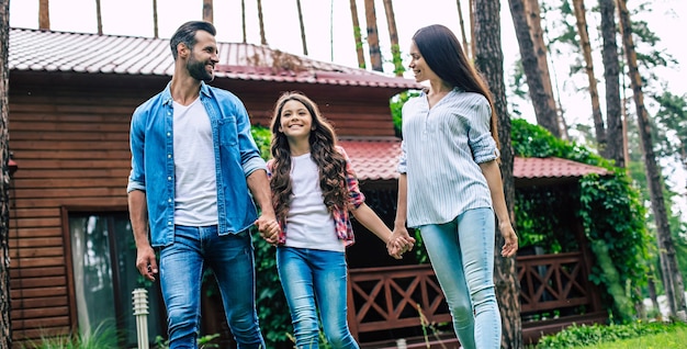 Young happy modern parents with a cute daughter are walking outdoors