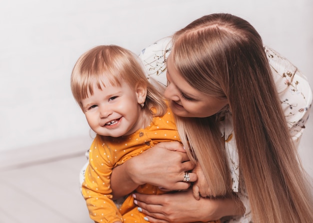 Young happy mom hugs her little laughing daughter. Mom and Her Child Having Fun together