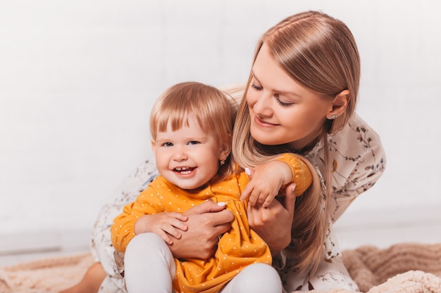 Young happy mom hugs her little laughing daughter. Mom and Her Child Having Fun together