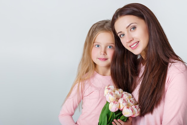 Young happy mother and daughter with bouquet of tulips