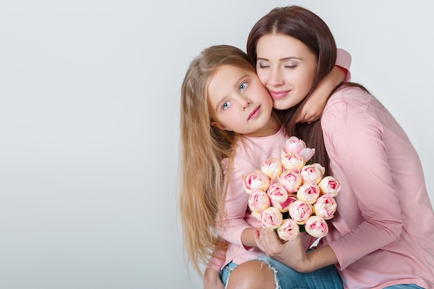 Young happy mother and daughter with bouquet of tulips