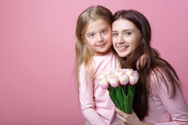 Young happy mother and daughter with bouquet of tulips