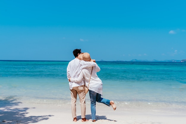 Young happy muslim couple white dress on seashore. 