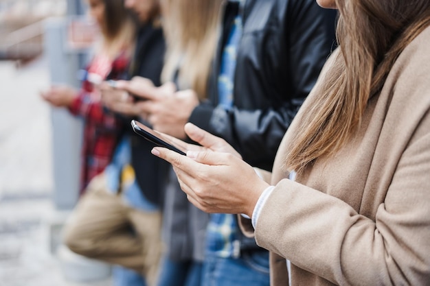 Young happy people using mobile phones outdoor - Focus on right woman hands holding smartphone