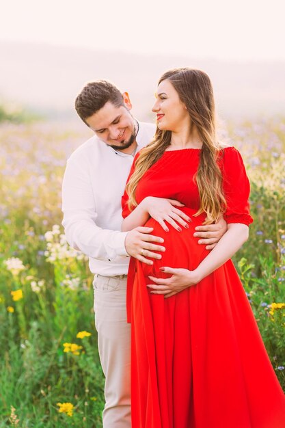 Young happy pregnant couple hugging in nature Concept of love relationship care marriage family creation pregnancy and parenting