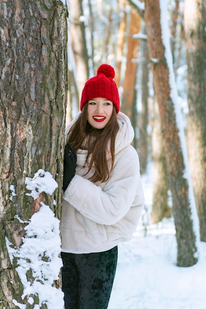 Young happy smiling brunette caucasian woman stands in coniferous snowy winter forest Vertical frame