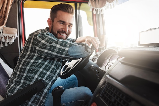 Young and happy smiling truck driver inside his vehicle