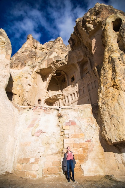 Young happy tourist woman traveler enjoying a vacation in stone ruins caves Cappadocia Turkey