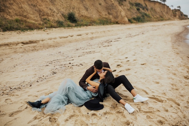 Young happy wedding couple relaxing together on tropical beach at azure sea.