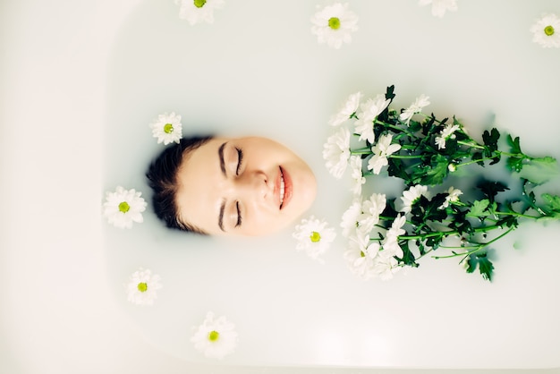 Young happy woman in the bathroom with flowers. Spa treatments