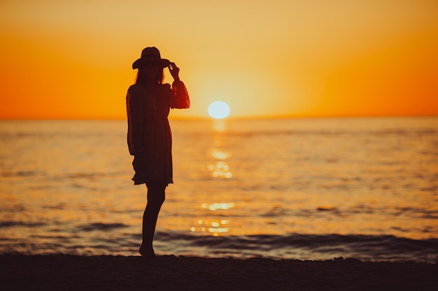 Young happy woman on the beach enjoy her summer vacation Beautiful woman in hat is happy and calm in her stay on the beach