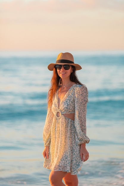 Young happy woman on the beach enjoy her summer vacation at sunset