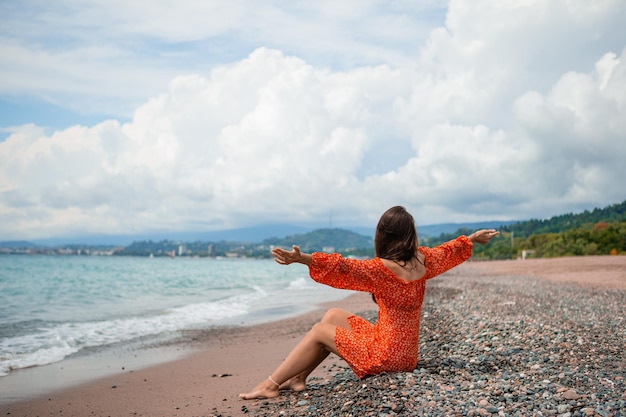 Young happy woman on the beach with mountain view