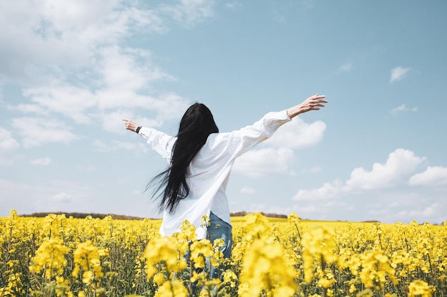 Young happy woman enjoying canola field.