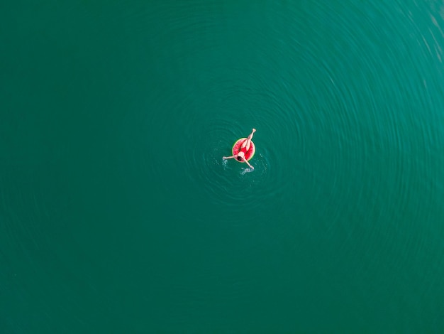 Young happy woman floating in blue azure water on inflatable ring circle summer vacation