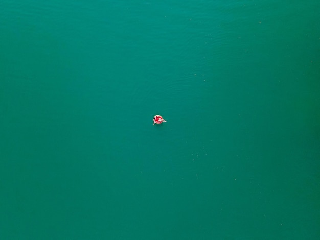 Young happy woman floating in blue azure water on inflatable ring circle summer vacation