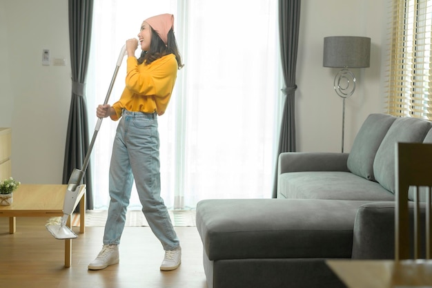 Young happy woman mopping and vacuum the floor in living room