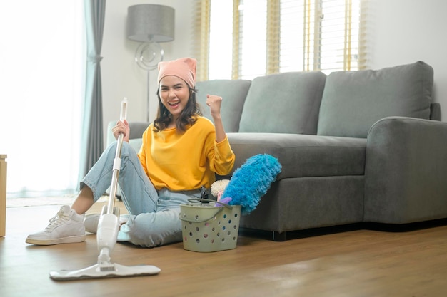 Young happy woman mopping and vacuum the floor in living room