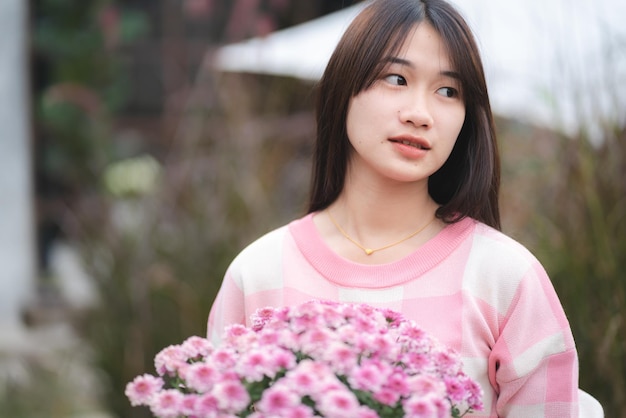 Young happy woman person smiling with pink flower blooming pretty cute girl portrait in summer with nature flower plant in pink color and colorful natural outdoor