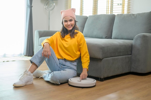 Young happy woman using Robotic vacuum cleaner in living room