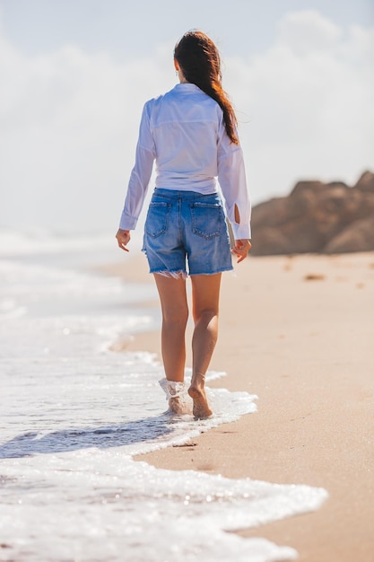 Young happy woman walking on the beach